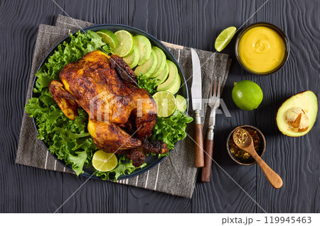 whole roasted chicken with avocado, lime on plate 119945463