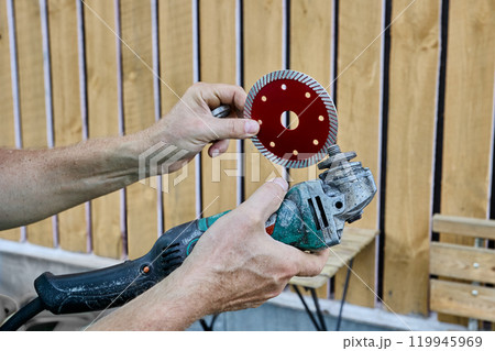 Replaceable diamond blade for cutting stone and concrete is installed on an angle grinder. Replaceable diamond blade for cutting stone and concrete is installed on an angle grinder. 119945969