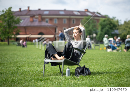 Relaxed woman rest with eyes closed while listen to lectures on laptop in park. Online school, study 119947470