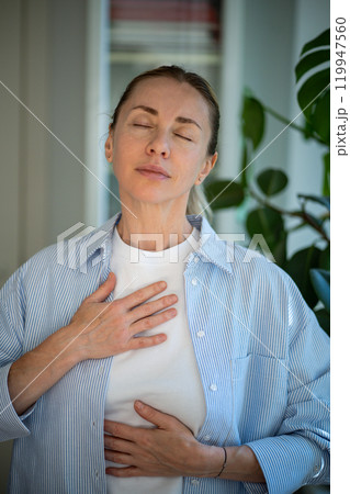 Peaceful calm woman holding hands on chest with closed eyes feels thankful, grateful for luck, fate. Peaceful calm woman holding hands on chest with closed eyes feels thankful, grateful for luck, fate. 119947560