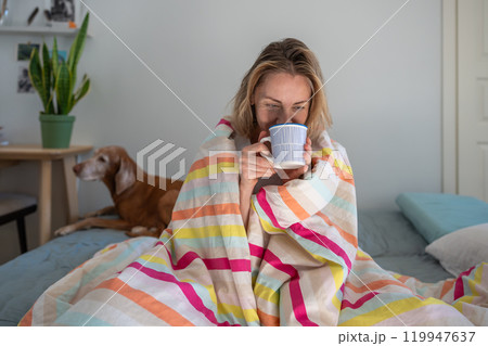 Lazy morning of happy woman wrapped in blanket in bed drinks morning coffee remembering good times. Lazy morning of happy woman wrapped in blanket in bed drinks morning coffee remembering good times. 119947637