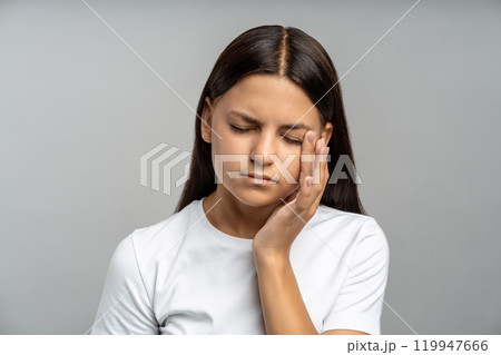 Unhappy sad teen girl facepalming, rubbing tired eyes against isolated gray wall. Heavy workload Unhappy sad teen girl facepalming, rubbing tired eyes against isolated gray wall. Heavy workload 119947666
