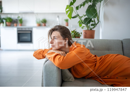 Thoughtful dreaming woman lying on sofa looking aside window enjoy calmness for tranquil relaxation. 119947847