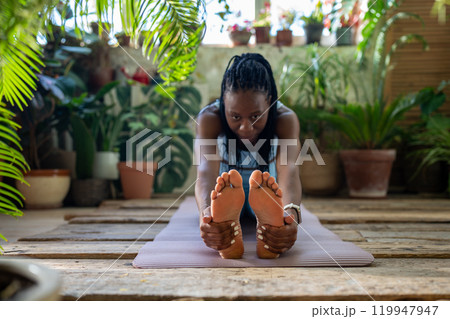 Athletic african american woman do flexibility exercise warm up muscles legs stretching back at home 119947947