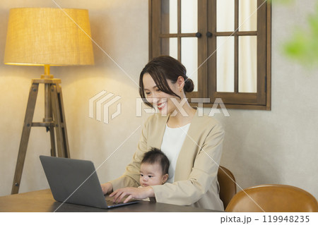赤ちゃんを抱っこして仕事するスーツを着た女性 赤ちゃんを抱っこして仕事するスーツを着た女性 119948235