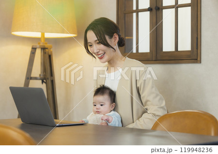 赤ちゃんを抱っこして仕事するスーツを着た女性 赤ちゃんを抱っこして仕事するスーツを着た女性 119948236