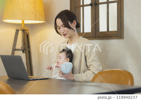 赤ちゃんを抱っこして仕事するスーツを着た女性 119948237