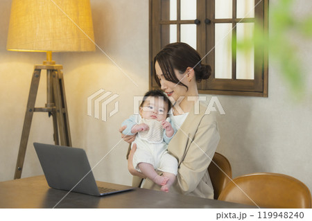 赤ちゃんを抱っこして仕事するスーツを着た女性 赤ちゃんを抱っこして仕事するスーツを着た女性 119948240