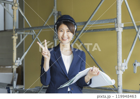 現場で図面を見るスーツの女性　 119948463