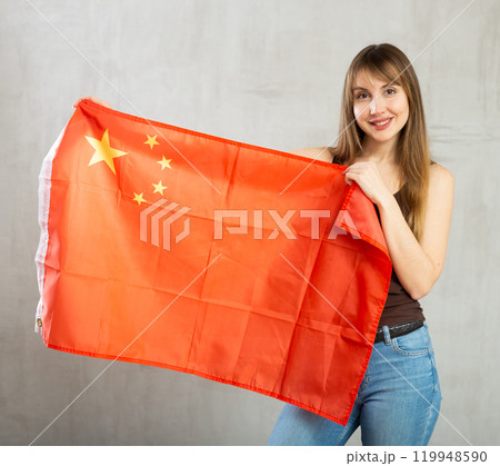 Joyful female fan of favorite team of China with the national flag in her hands Joyful female fan of favorite team of China with the national flag in her hands 119948590