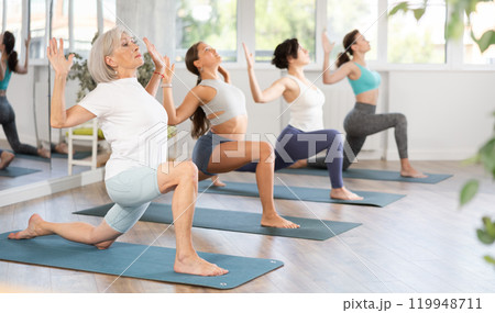 Elderly woman doing pilates in group in studio Elderly woman doing pilates in group in studio 119948711