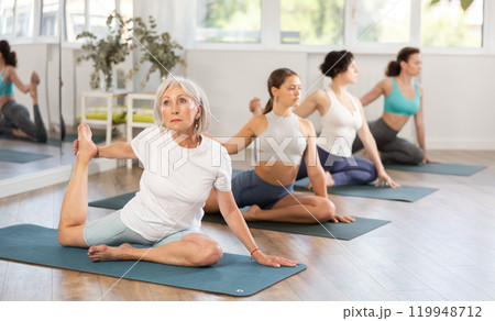 Elderly woman doing one legged king pigeon pose during yoga training 119948712