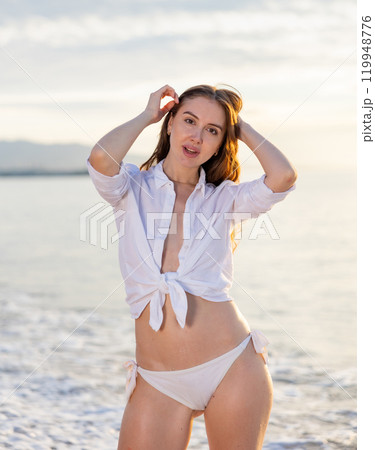 Beautiful woman with blond hair in elegant bikini posing on sunset beach 119948776