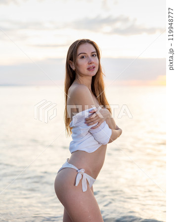 Young sexy girl playfully posing at beach on sunset 119948777