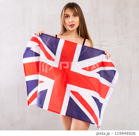 Young woman hiding behind flag of Great Britain Young woman hiding behind flag of Great Britain 119948826