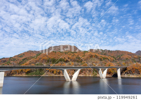 紅葉した低い山と湖に映る橋 119949261