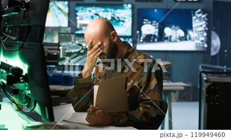 Tired military officer receiving intel folder on enemy, feeling fatigued. Overworked army specialist feeling exhausted while reading mission case file to collect data on opponents strategy, camera A Tired military officer receiving intel folder on enemy, feeling fatigued. Overworked army specialist feeling exhausted while reading mission case file to collect data on opponents strategy, camera A 119949460