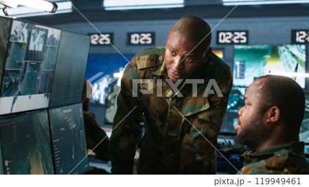 Team of soldiers looking at screens in command center housing operational missile defense system designed to intercept ballistic rockets. Tracking equipment operators using radar systems, camera A Team of soldiers looking at screens in command center housing operational missile defense system designed to intercept ballistic rockets. Tracking equipment operators using radar systems, camera A 119949461