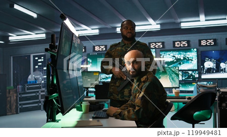 Soldier doing tasks in military base, doing surveillance with digital radar equipment, operating missile systems. Middle Eastern man monitoring army HQ CCTV for any unauthorized activity, camera B 119949481