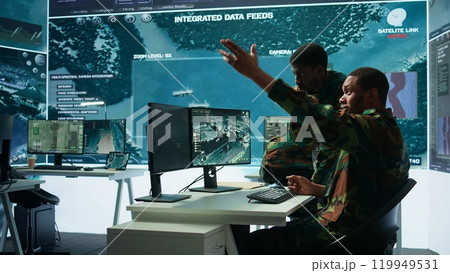 Government analysts work in an advanced command center with satellite radar systems, overseeing surveillance activities and interpreting real time data. Protecting national interests. Camera B. Government analysts work in an advanced command center with satellite radar systems, overseeing surveillance activities and interpreting real time data. Protecting national interests. Camera B. 119949531