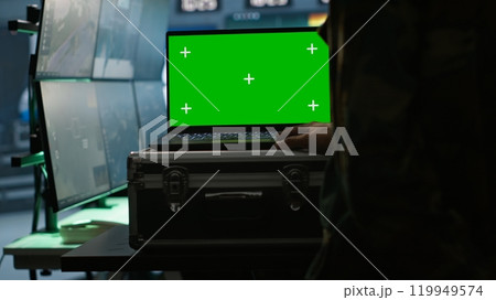 Army specialist working in war room operating surveillance tech, evaluating target data on isolated screen laptop. Soldier engaging enemy forces using chroma key notebook, camera A 119949574