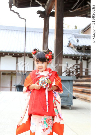 七五三詣で可愛い三歳の女の子、神社仏閣での和装ロケーション撮影、被布キッズフォト家族写真 119950268