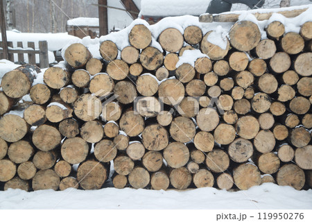 The firewood is neatly stacked. Firewood made of natural wood is laid and prepared for the winter in a stack of round logs. 119950276