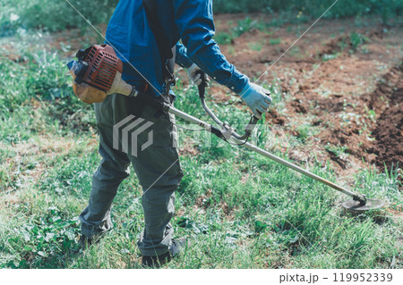 エンジン式刈払い機で草刈りをする男性 119952339