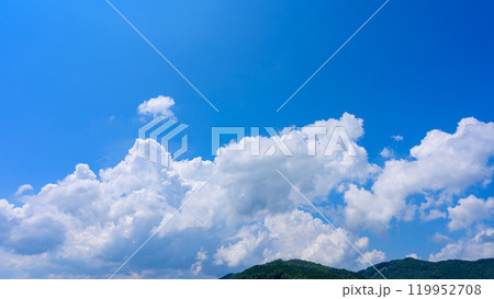 夏の青空のもと、山頂に流れるたくさんの白い雲 夏の青空のもと、山頂に流れるたくさんの白い雲 119952708