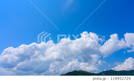 夏の青空のもと、山頂に流れるたくさんの白い雲 119952729