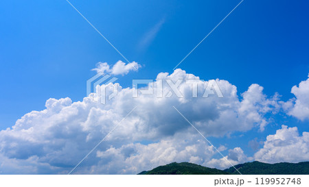 夏の青空のもと、山頂に流れるたくさんの白い雲 119952748