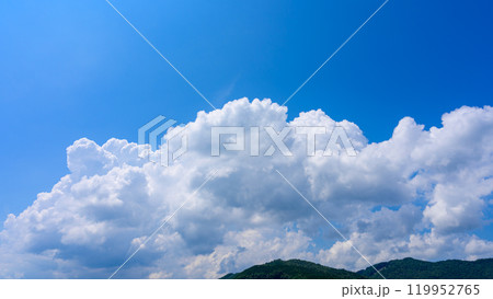 夏の青空のもと、山頂に流れるたくさんの白い雲 夏の青空のもと、山頂に流れるたくさんの白い雲 119952765