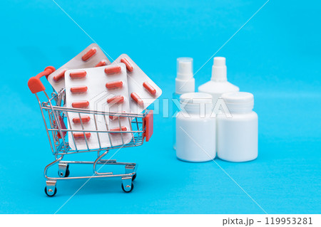 Pills and Capsules in Shopping Cart on Blue Background Pills and Capsules in Shopping Cart on Blue Background 119953281