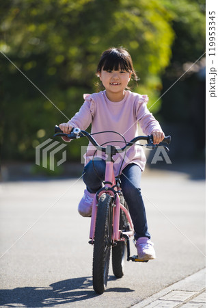 自転車の練習に挑戦する小学生の女の子 自転車の練習に挑戦する小学生の女の子 119953345