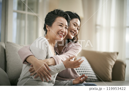 asian adult daughter and senior mother hugging each other at home asian adult daughter and senior mother hugging each other at home 119953422