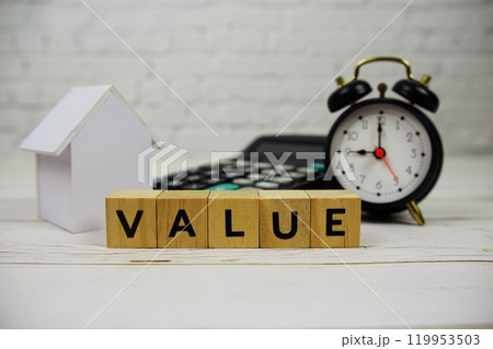 Value with wooden blocks alphabet letters and alarm clock, calculator, white house model on wooden background Value with wooden blocks alphabet letters and alarm clock, calculator, white house model on wooden background 119953503