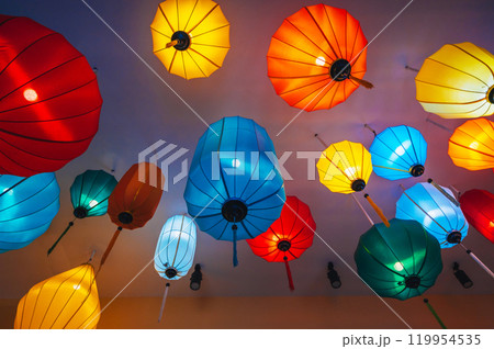 Traditional multicolored silk hanging Chinese lanterns from ceiling of an Asian cafe for interior decoration 119954535