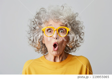 Joyful very surprised 70 year old American woman with big amazed eyes and surprised mouth, with intense makeup, red lips, hair styling and rose-colored glasses. Live emotions. Idea for advertising 119955065