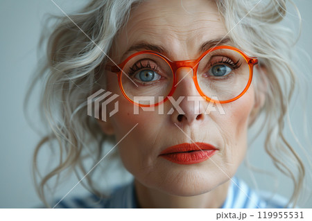 An elegant elderly lady with a modern hairstyle and soft blue eyes. The look is filled with confidence and inner peace. Concept of a successful and stylish woman. Classic atmosphere and modern style. 119955531