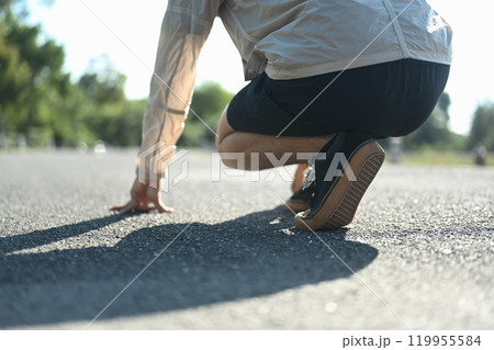 Low angle view of athlete in a starting position on the ground ready to sprint Low angle view of athlete in a starting position on the ground ready to sprint 119955584