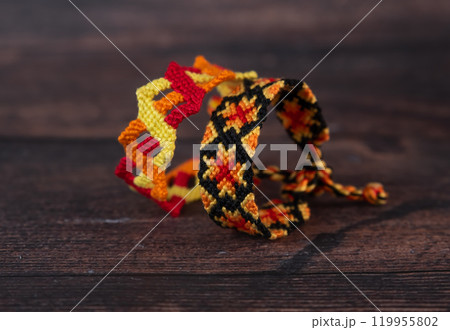 Tied woven friendship bracelets with bright colorful patterns handmade of thread isolated on white background Tied woven friendship bracelets with bright colorful patterns handmade of thread isolated on white background 119955802