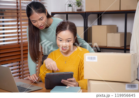 Two young asian woman working on tablet while managing and planning online business. Two young asian woman working on tablet while managing and planning online business. 119956645
