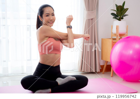 Beautiful young asian woman sitting workout with warmup and stretch muscle arm and hands. 119956742