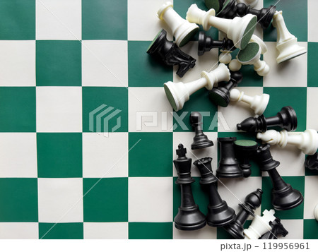 Chessboard and fallen chess pieces on green and white checkered board Chessboard and fallen chess pieces on green and white checkered board 119956961