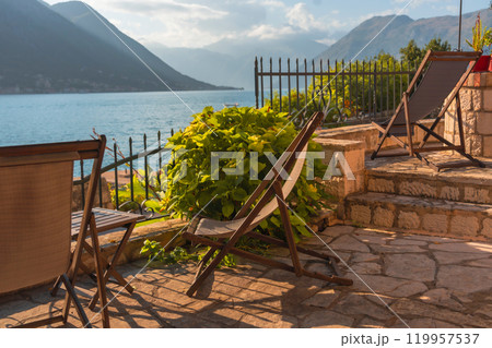 A seafront terrace with a couple of sun loungers in soft evening light A seafront terrace with a couple of sun loungers in soft evening light 119957537
