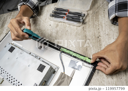 Man technician repairing television with a screwdriver Man technician repairing television with a screwdriver 119957799