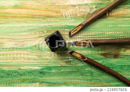 Set of calligraphy reeds covered ink with inkwell on wooden background Set of calligraphy reeds covered ink with inkwell on wooden background 119957828