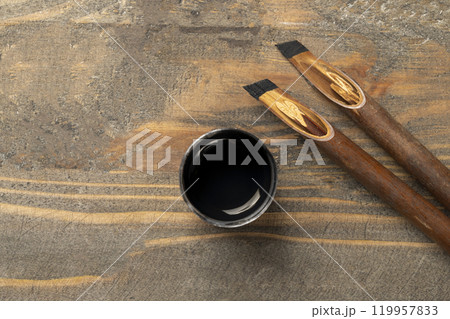 Calligraphy reeds covered ink with inkwell on wooden background Calligraphy reeds covered ink with inkwell on wooden background 119957833