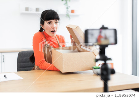 Caucasian female blogger surprised while unboxing during live streaming 119958074