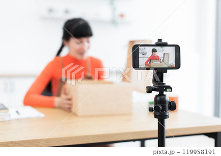 Caucasian female blogger unpacking goods during live streaming session Caucasian female blogger unpacking goods during live streaming session 119958191